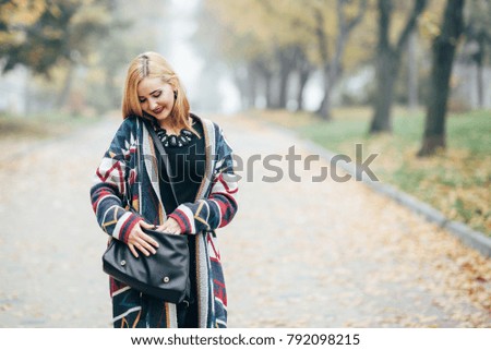 Cute blonde walking along the ridge of an autumn park in black dress and top dress