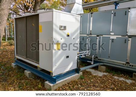 Commercial air handling unit with big condensing unit standing outdoor on the ground covered by fallen leaves Royalty-Free Stock Photo #792128560