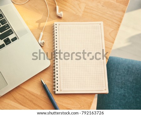 Notepad, laptop and headphones on the wooden desk