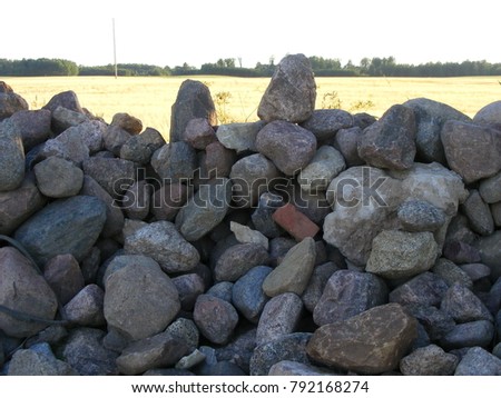 Boulders stack at the roadside. Stone of different sizes. Natural landscape background of countryside. Horizontal view.