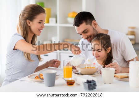 family, eating and people concept - happy mother, father and daughter having breakfast at home Royalty-Free Stock Photo #792202816