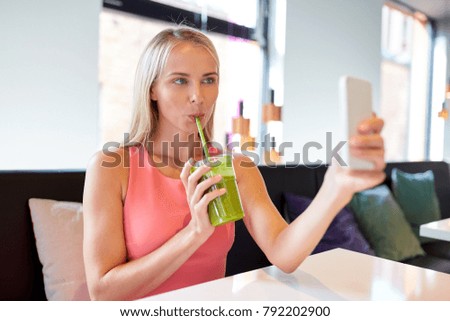 technology, people and leisure concept - happy woman with smartphone and smoothie drink or vegetarian shake taking selfie at restaurant