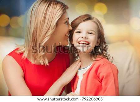 family and people concept - happy mother and daughter whispering something into ear over festive lights background