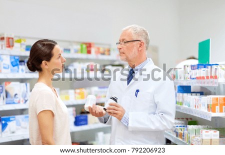 medicine, healthcare and people concept - senior apothecary with drugs and female customer at pharmacy Royalty-Free Stock Photo #792206923