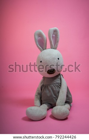 White rabbit doll on a pink background.