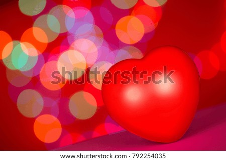 The red heart is on blur colorful bokeh background, love concept for Valentine`s day.