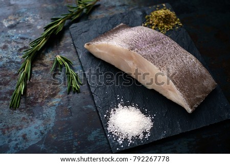 fresh steak raw fish halibut on the stone with the salt and herbs on steel background