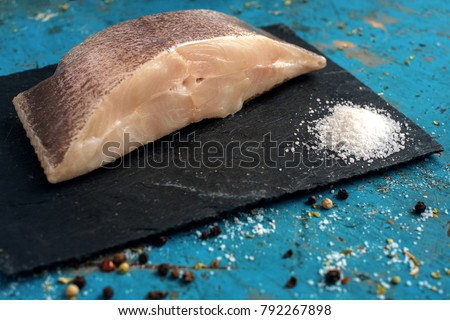 fresh steak raw fish halibut on the stone with the salt and herbs on wooden background