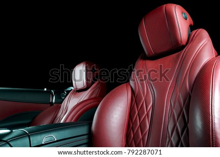 Modern Luxury car inside. Interior of prestige modern car. Comfortable leather seats. Red perforated leather cockpit with isolated Black background. Modern car interior