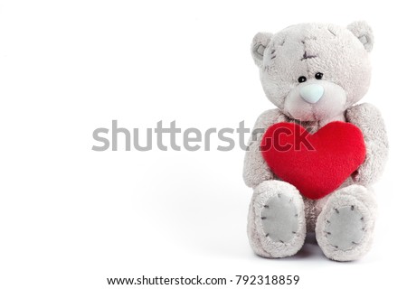 Teddy bear isolated on white background holding a pillow in the shape of a heart