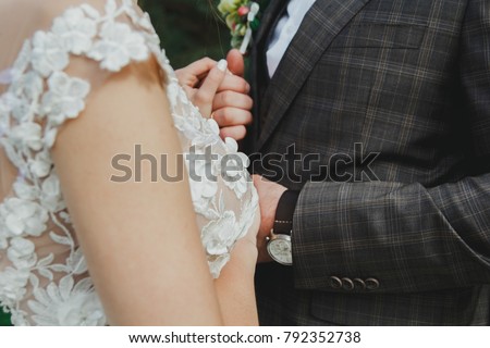 Beautiful wedding couple holding hands. It's such an exciting moment. Vintage wedding dress and plaid men's costume. Bride and groom are hugging at their wedding photo shoot. Great Gatsby style.