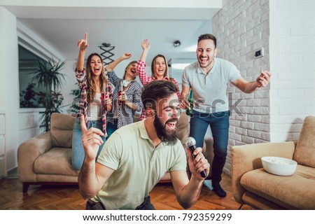 Group of friends playing karaoke at home. Concept about friendship, home entertainment and people Royalty-Free Stock Photo #792359299