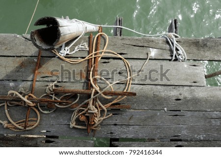 Rusty metal anchor on wood floor with bamboo stairs over the sea