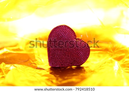 Red heart shape closeup on abstract yellow neon blur background. Concept of Valentine's Day