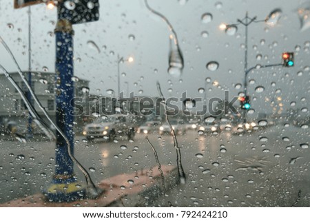 Road view through car window with rain drops, Driving in rain. Blurred background. 