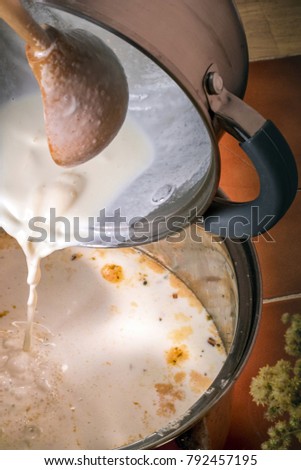 Milk is poured into saucepan. Preparation of milk soup. Stream of milk is poured into a saucepan. Top view, vertical photograph.
