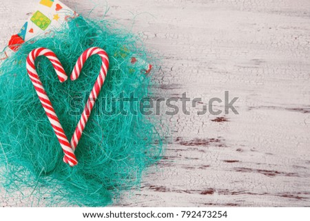 Two candy canes laid in shape of heart on white wooden background. Christmas or Valentine's day concept in minimalist style.