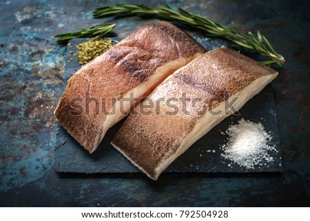 raw steak of sea fish on the rock with salt and rosemary on iron background