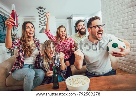 Happy friends or football fans watching soccer on tv and celebrating victory at home.Friendship, sports and entertainment concept. Royalty-Free Stock Photo #792509278