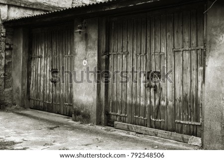 old wooden door in poor quarter. Ancient vintage wooden in an old wall. Traces of destruction, wooden gate and vintage fence, rusty metal nails. Conceptual background of ruin and poverty