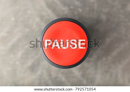 Overhead of a red pause push button over a blurred gray background Royalty-Free Stock Photo #792571054