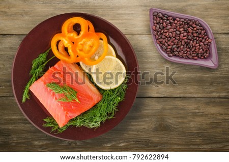red fish trout fillets on a plate. fish trout on a wooden background. trout with dill, lemon and pepper