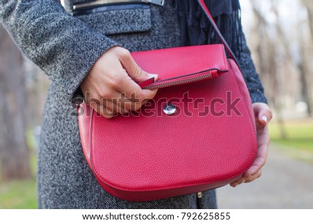Close up picture of red leather bag and female hand outdoor on wintertime
