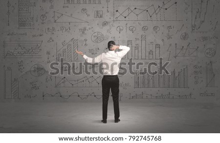 A successful confident businessman thinking about decisions, standing in front of wall full with graph pie charts and calculations concept