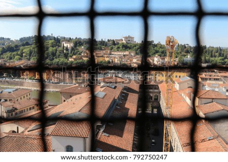 The view from over an iron grid of Palazzo Vecchio window on Florentine cityscape in a sunny day. Florence, Tuscany, Italy.