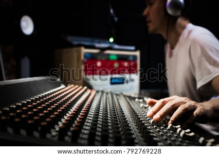 asian male dj, sound engineer, music producer working on sound mixer in recording, broadcasting studio. focus on hands