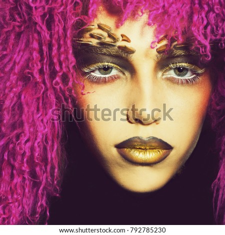 Closeup portrait of one beautiful wild young woman with bright golden animal monkey makeup with thorns on face in fur violet wig in studio, square picture
