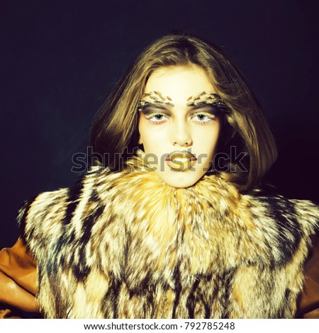 Closeup portrait of one beautiful wild young woman with bright golden animal monkey makeup with thorns on face in fur coat on black background, square picture