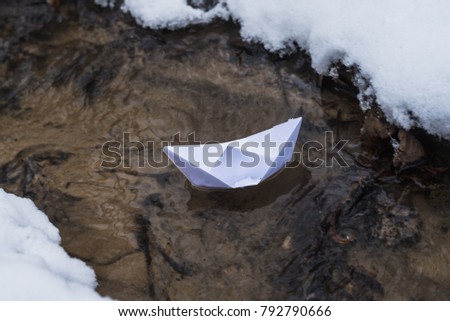 Origami boat of paper floats in the spring brook