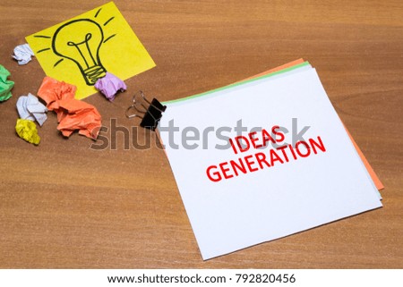 Idea concept with crumpled paper lightbulb and colored spiral notepad with pen on wooden desktop.