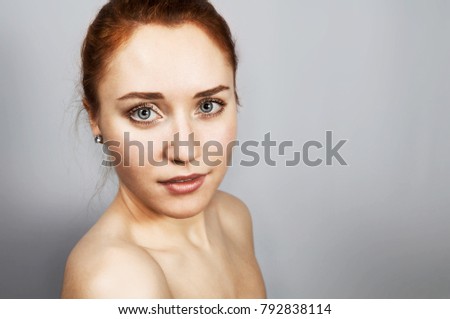 Red-haired girl looking forward on gray background