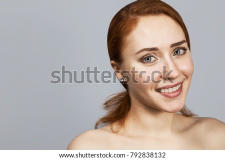 Red-haired girl smiles looking forward on gray background