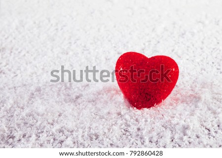Red glass heart on white artificial snow