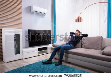 Young Man Relaxing On Sofa Near Television At Home Royalty-Free Stock Photo #792865525