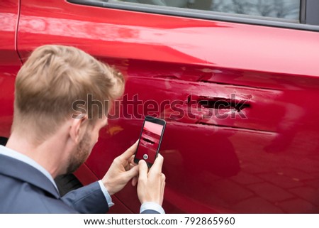 Close-up Of A Person Taking Picture Of Damaged Car On Mobile Phone