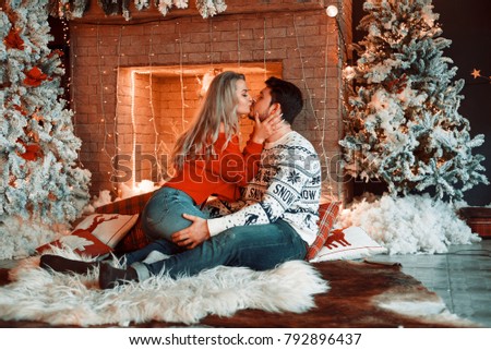 Man kisses his wonderful wife near the fireplace, christmas atmosphere