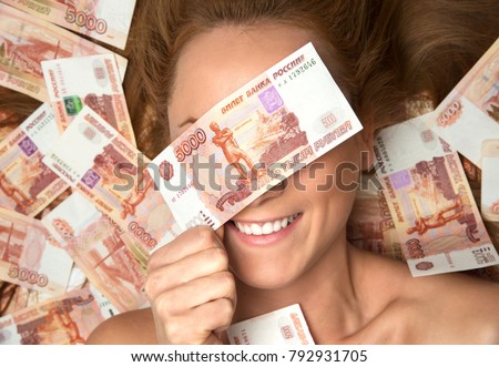 Young woman lying down with many cash money five thousand russian rubles notes close eyes isolated on a white background