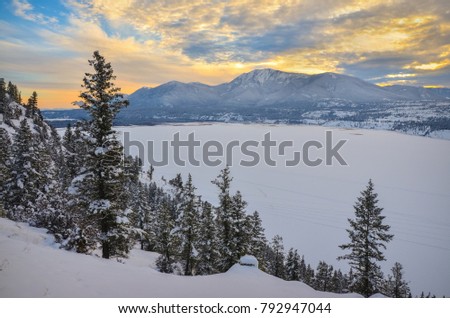 Winter Sunset over a snow covered Columbia Lake looking at the Purcell Mountains, British Columbia, Canada Royalty-Free Stock Photo #792947044