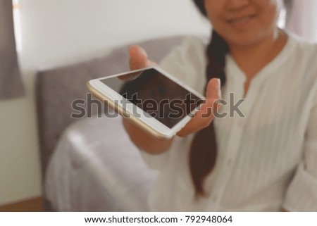 Smiling woman holding smart phone and send to everyone at bedroom ,selective focus