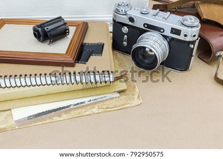 nostalgia concept. classic camera, photo frame, old pictures and film roll on kraft paper background.