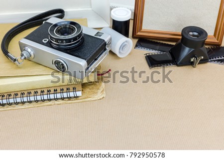 vintage camera, notebooks, aged photos, frames, negative films and lenses on brown paper background