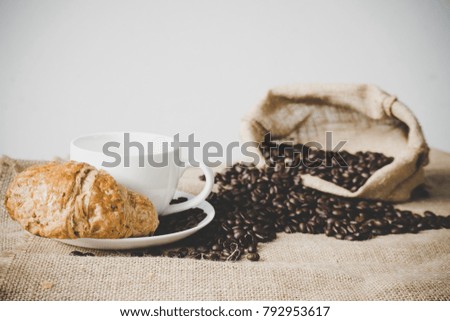 white cup of coffee with croissant and coffee beans (selective focus)