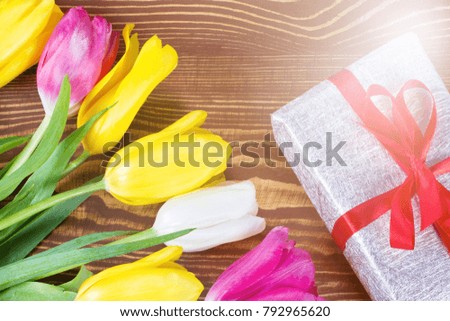 Gift box and tulips bouquet on  wooden background 