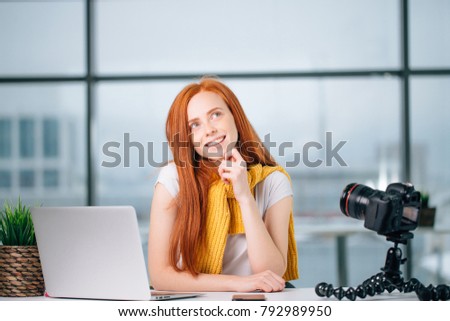 happy redhead female blogger with laptop think about new theme for vlog.