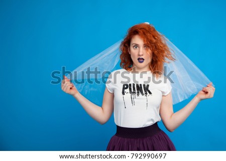 Isolated portrait of a red-haired girl of an extraordinary bride, on a blue background, with blue lips. Place fof text