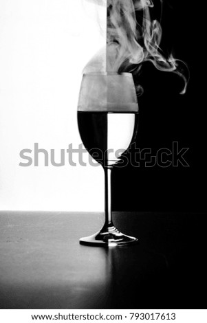 a glass of water and smoke on a black and white background close up